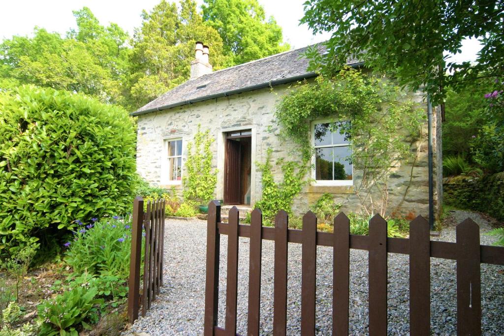 ein Haus mit einem Zaun und einem Hund darüber in der Unterkunft Springburn Cottage in Strachur