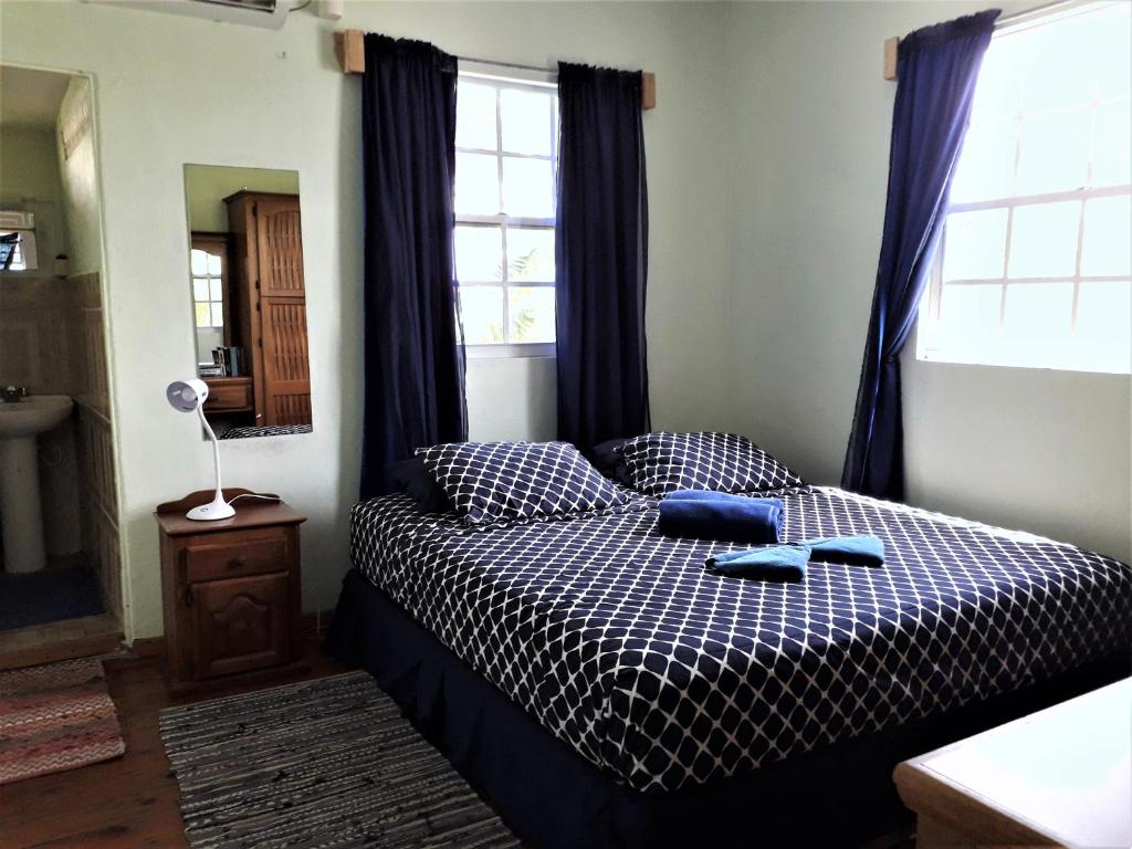 a bedroom with a bed with a black and white comforter at Miller's Guest House in Buccoo