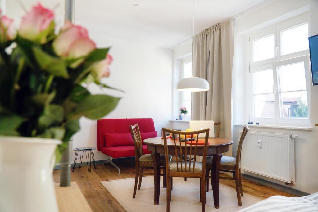 a living room with a table and chairs and a red couch at Apartment Dompredigergasse in Naumburg