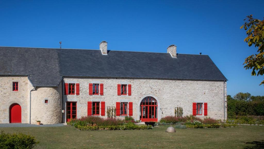a large white building with red windows and a black roof at Au Manoir des Loges in Quettreville-sur-Sienne