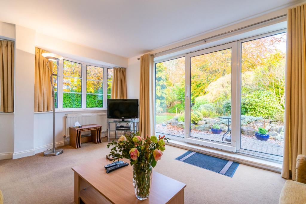 una sala de estar con un jarrón de flores sobre una mesa en The Garden Apartment en Bramhall