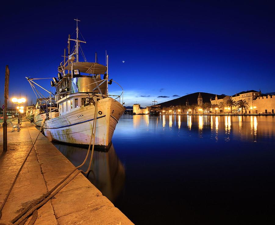 un barco está atracado en un puerto por la noche en Blue View Apartments, en Trogir