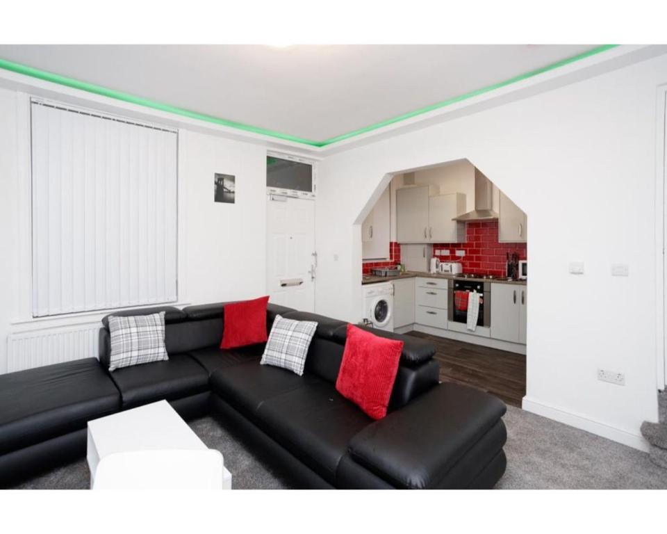 a living room with a black couch and a kitchen at CARTER HOUSE APARTMENTS.....6 beds in 3 bedrooms in Leeds