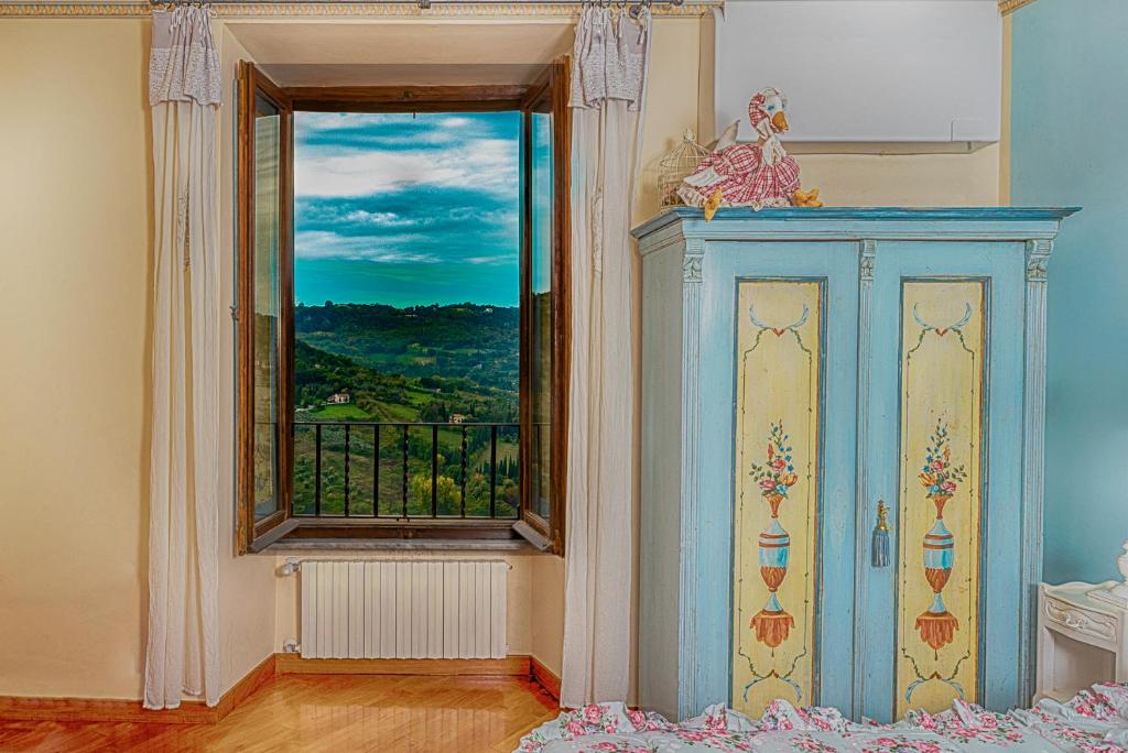 a bedroom with a window and a blue cabinet at Ripa Medici, camere con vista e parcheggio incluso in Orvieto