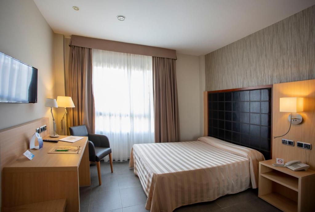 エヘア・デ・ロス・カバジェロスにあるHotel Salvevirのベッドとデスクが備わるホテルルームです。