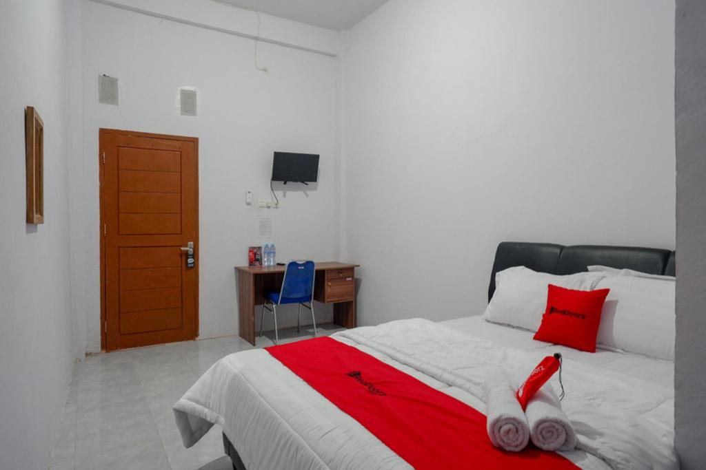 Schlafzimmer mit einem Bett mit rotem Umhang in der Unterkunft RedDoorz near Pasar Baru Mamuju in Mamuju