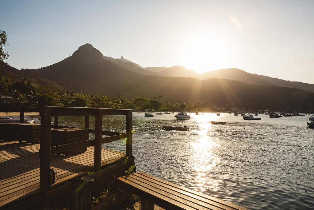 a dock with boats in the water with mountains at Che Lagarto Hostel Ilha Grande in Abraão