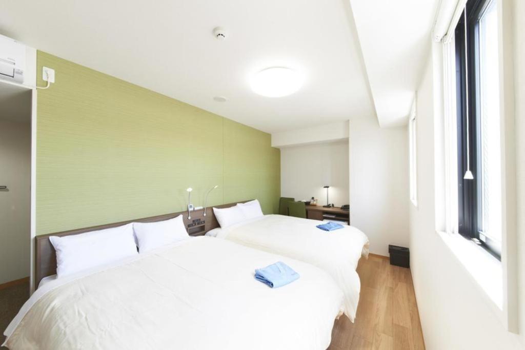 1 Schlafzimmer mit 2 weißen Betten und einem Fenster in der Unterkunft Hotel Sun Clover Koshigaya Station - Vacation STAY 55377 in Koshigaya