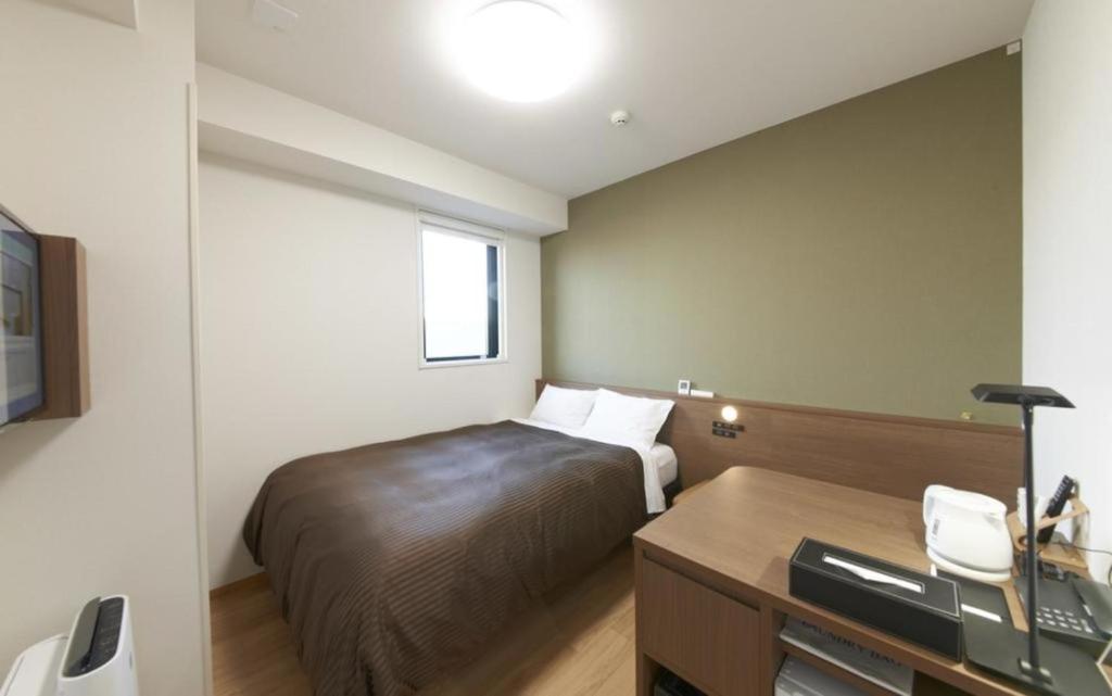 um quarto de hotel com uma cama e uma secretária em Hotel Sun Clover Koshigaya Station - Vacation STAY 55372 em Koshigaya