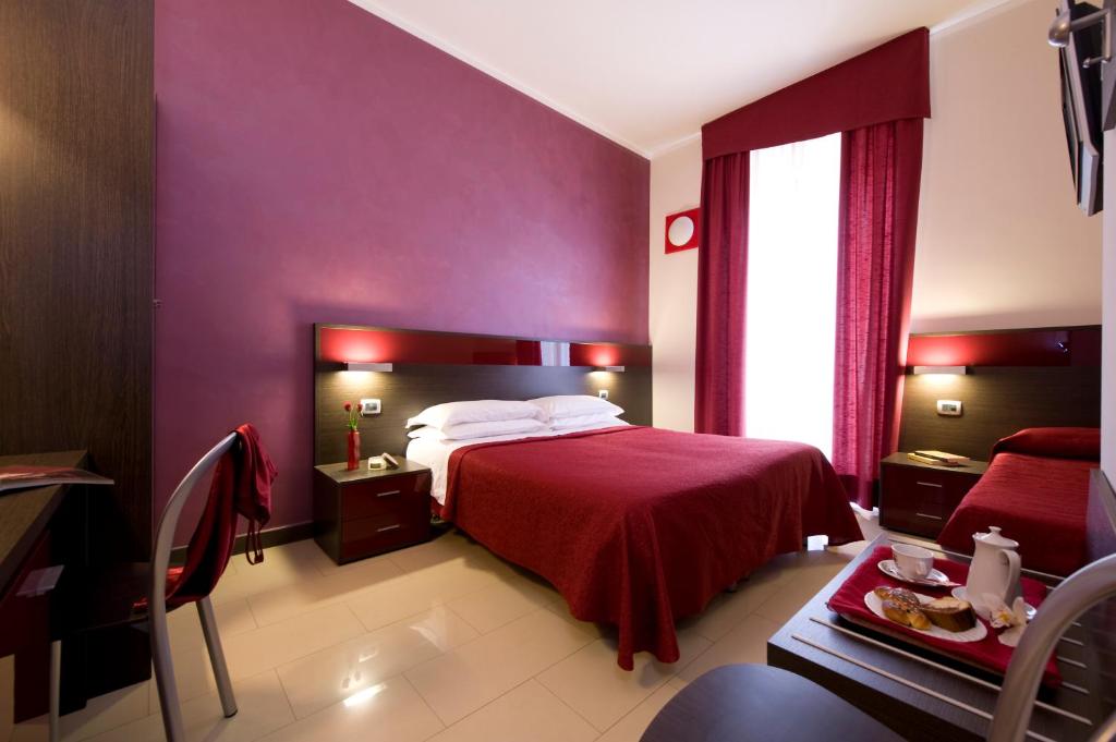 ミラノにあるホテル イデアーレの紫の壁のベッドルーム1室、赤いベッドカバー付きのベッド1台が備わります。