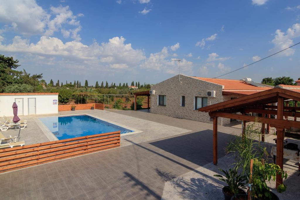 a backyard with a swimming pool and a house at BerryRose Villa in Pervolia