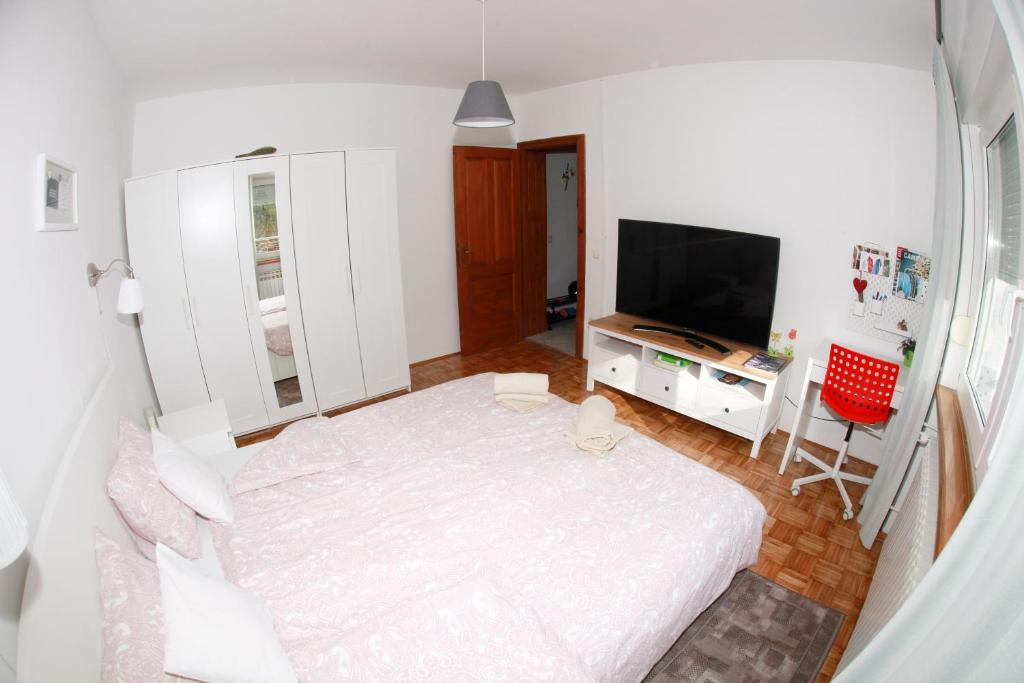 a white bedroom with a bed and a television at Apartment Magnolija in Karlovac
