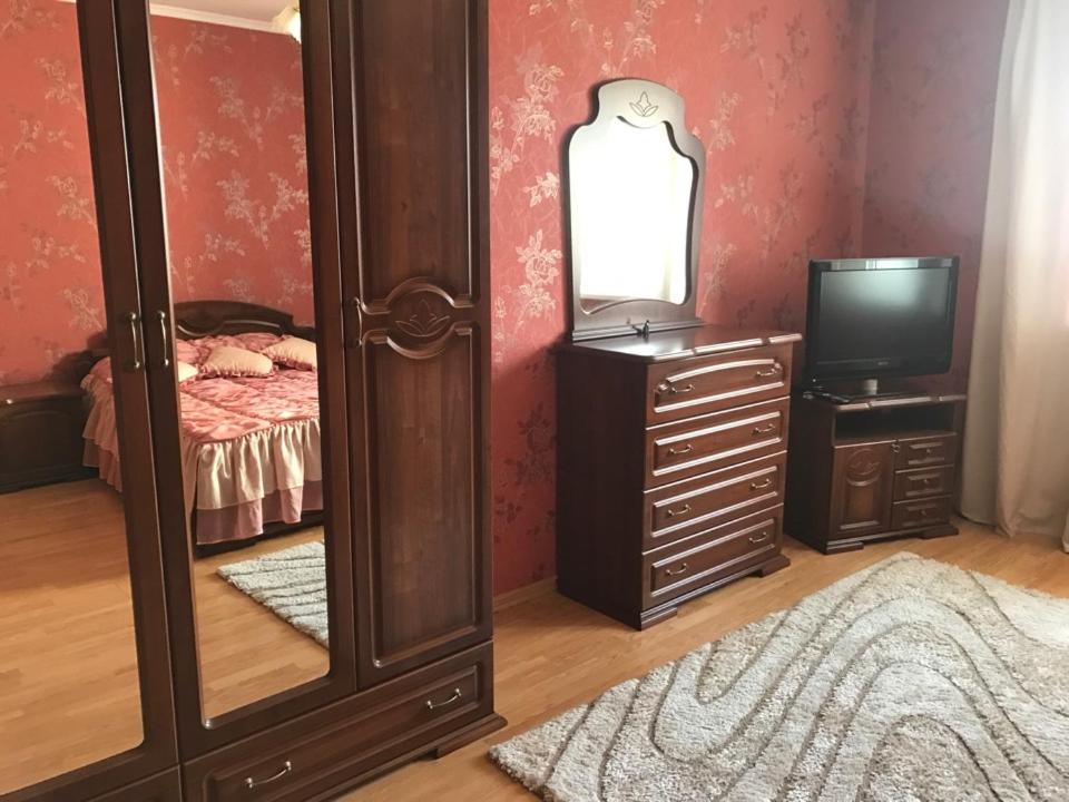 a bedroom with a mirror and a dresser with a television at Двухкомнатные апартаменты в центре города Карла Маркса 163 in Tambov