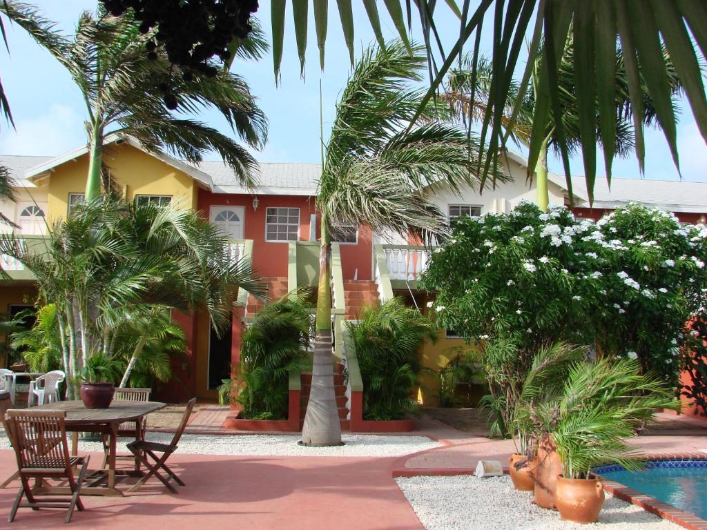 a courtyard with a table and palm trees and a building at Cunucu Villas - Aruba Tropical Garden Apartments in Oranjestad