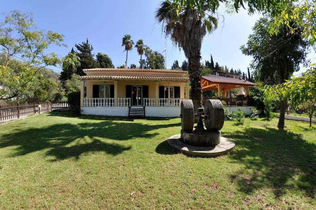 a house with a large yard with a statue in front of it at SPITI MAGDALINI in Agios Georgios Pagon