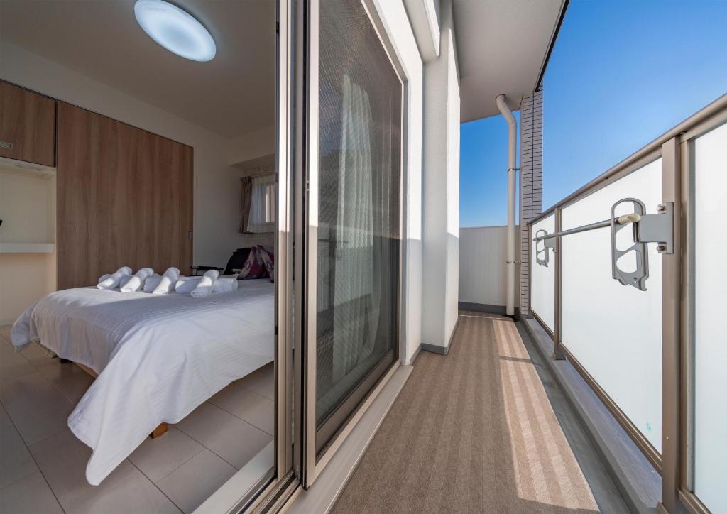 a bedroom with a bed and a balcony at Meet Me Umeda Nishi in Osaka