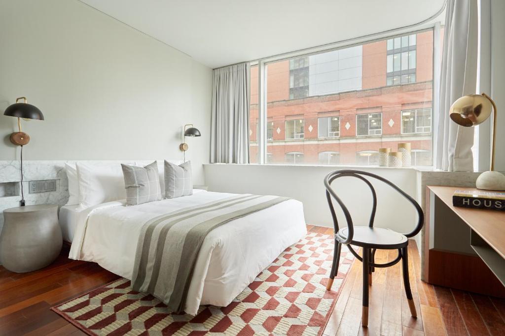 1 dormitorio con 1 cama, 1 silla y 1 ventana en Sonder The Slate, en Toronto