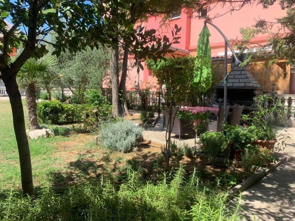 un jardin en face d'une maison rose dans l'établissement Apartments Anna - peaceful and quiet, à Batalaži