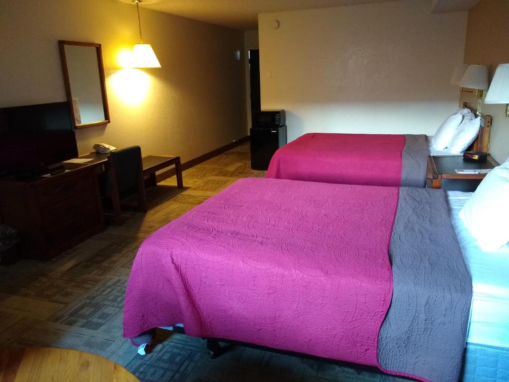 two beds in a hotel room with pink blankets at The Wilderness Inn in Enterprise