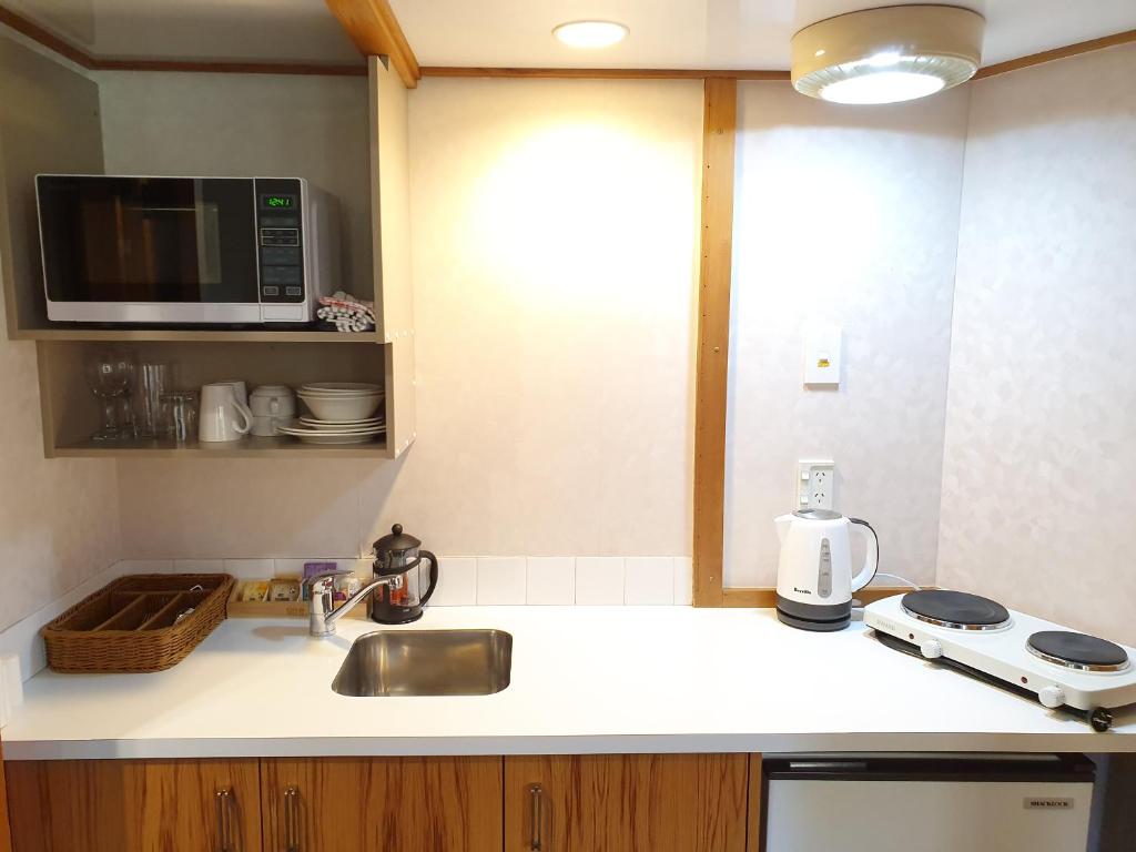 a kitchen counter with a sink and a microwave at Fitzherbert Castle Motel in Palmerston North