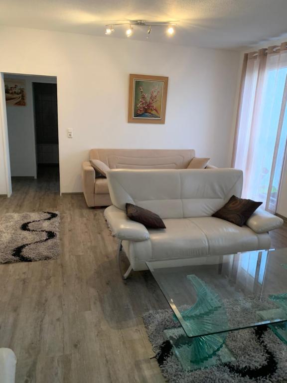 a living room with a white couch and a glass table at Feuerbachstr.9 Ferienwohnung in Bottrop