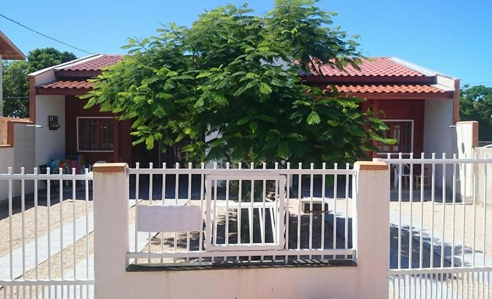 una cerca blanca frente a una casa con un árbol en Casa do Jefferson, en Bombinhas