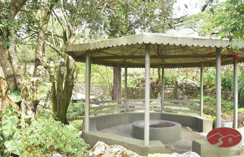 a pavilion with a fire pit in a garden at Skyland Garden Hotel and Resort in Baguio