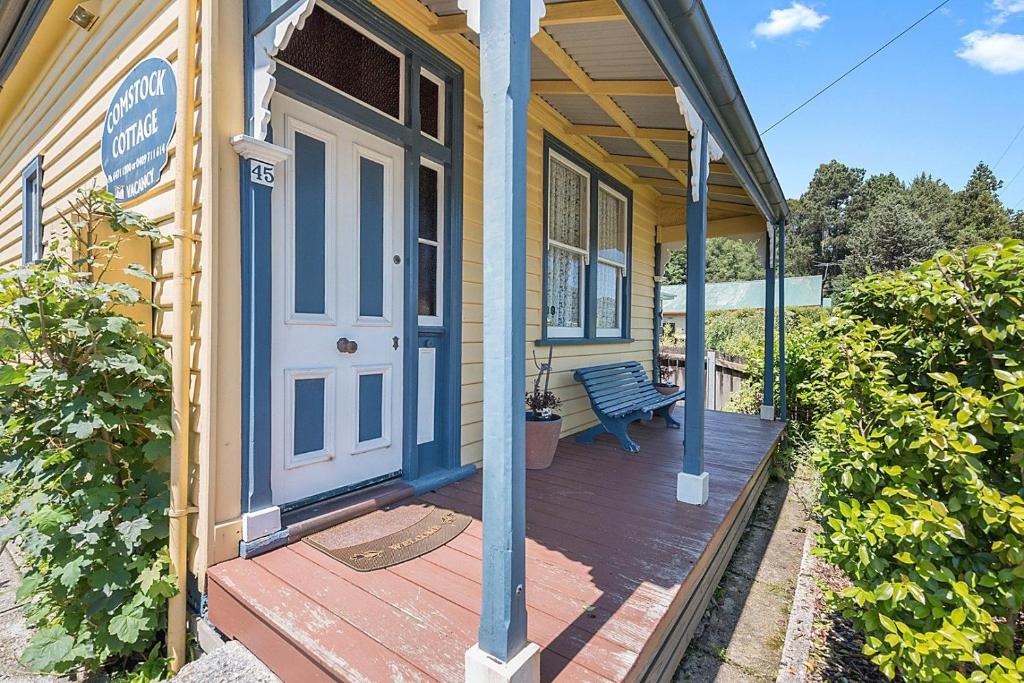 a porch of a house with a blue door and a bench at Comstock Cottage Welcomes You in Queenstown