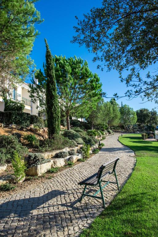 a park bench sitting on a stone path at Vale d'El Rei Hotel & Villas in Carvoeiro