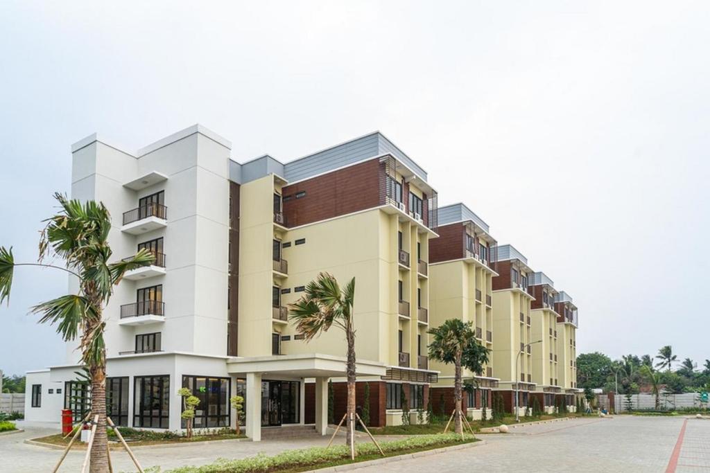 a building with palm trees in front of it at RedDoorz Plus @ EcoHome Citra Raya Tangerang in Tangerang