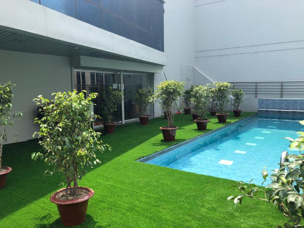 a green lawn in front of a pool of water at Hotel Sarina in Dhaka