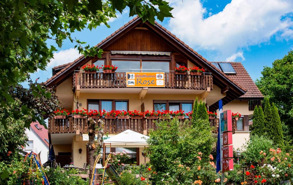 una casa con un balcón con flores rojas. en Haus Rose, en Allensbach