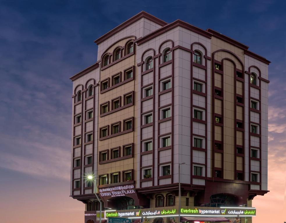 un edificio blanco alto con una puesta de sol en el fondo en Downtown Plaza Hotel Apartment Pet Friendly, en Abu Dabi