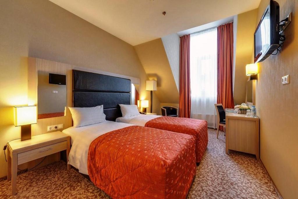 a hotel room with two beds and a television at New Peterhof Hotel in Petergof