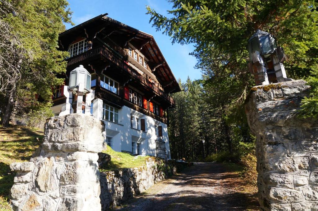 a house in the woods with a stone wall at Chalet Surselva in Arosa
