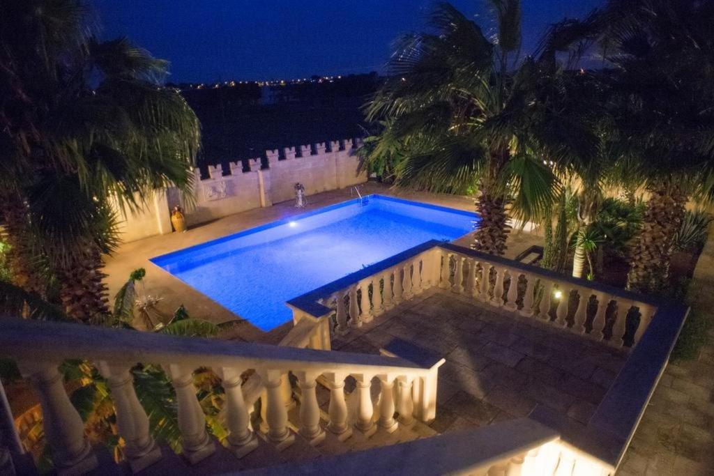 basen w nocy z płotem i palmami w obiekcie Michelle House w mieście Torre Suda