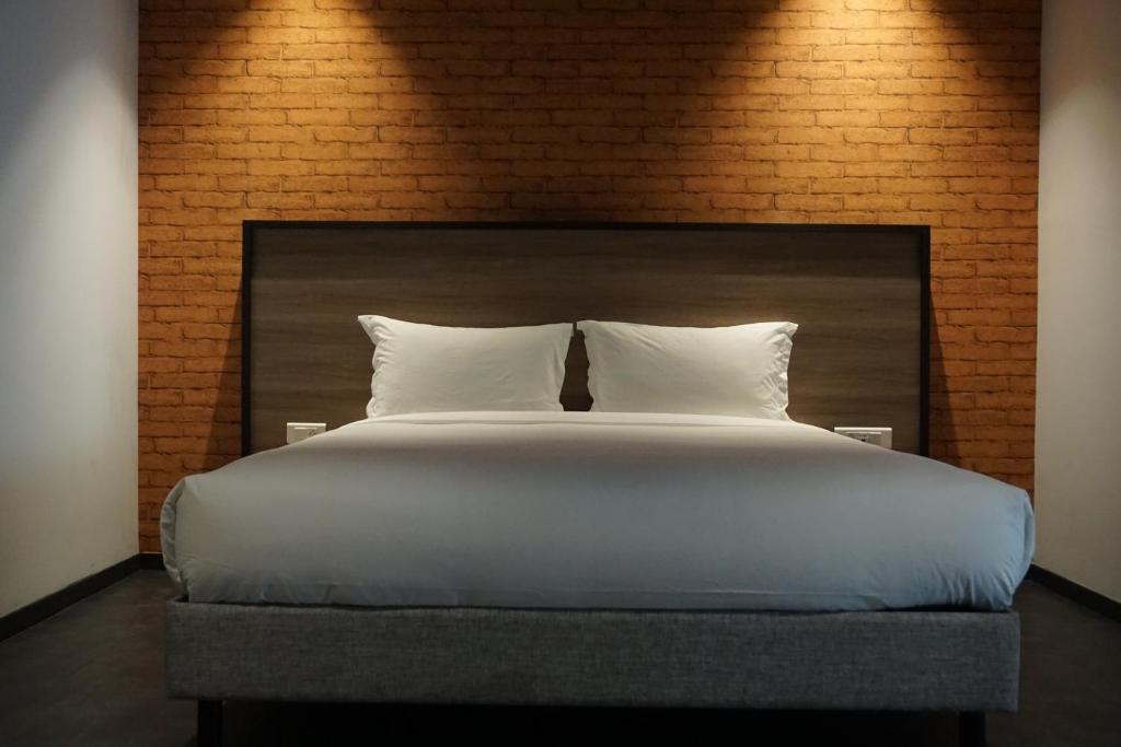 a large bed with white pillows and a brick wall at ONOMO Hotel Tanger Med in Tangier