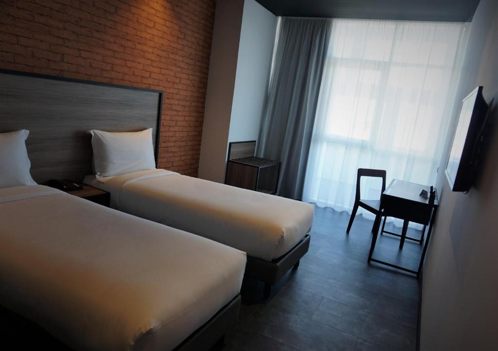 a hotel room with two beds and a chair at ONOMO Hotel Tanger Med in Tangier