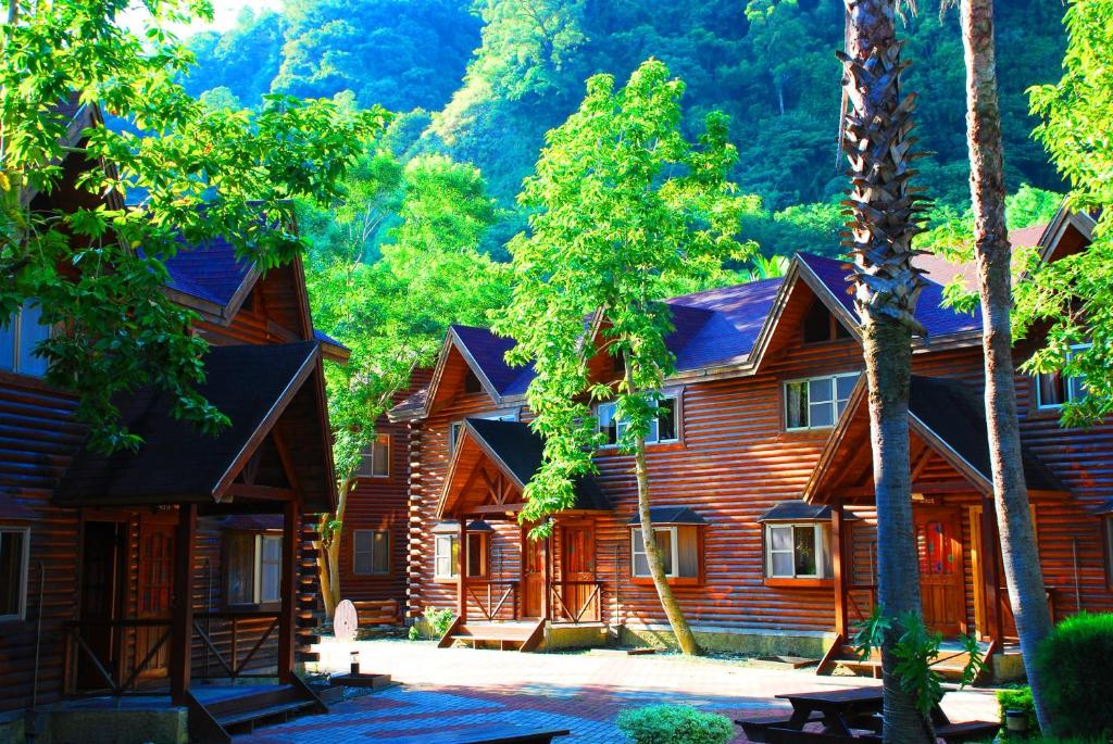 Cabaña de madera con árboles y montañas al fondo en Master Bear Resort en Jiafeng