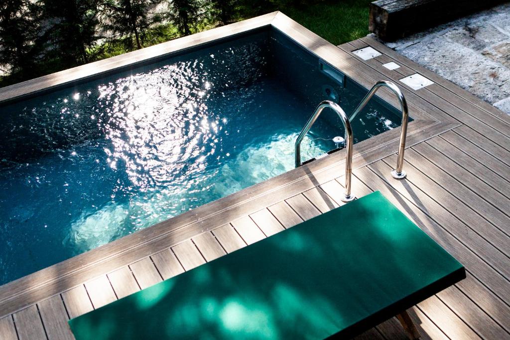 una gran piscina con terraza de madera y alfombra verde en Il Lavatoio, en Cissano