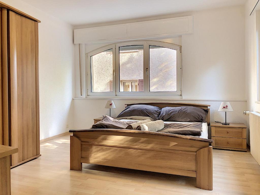 Schlafzimmer mit einem Bett mit einem Holzrahmen und einem Fenster in der Unterkunft Apartment Del Sol Sion Center in Sion