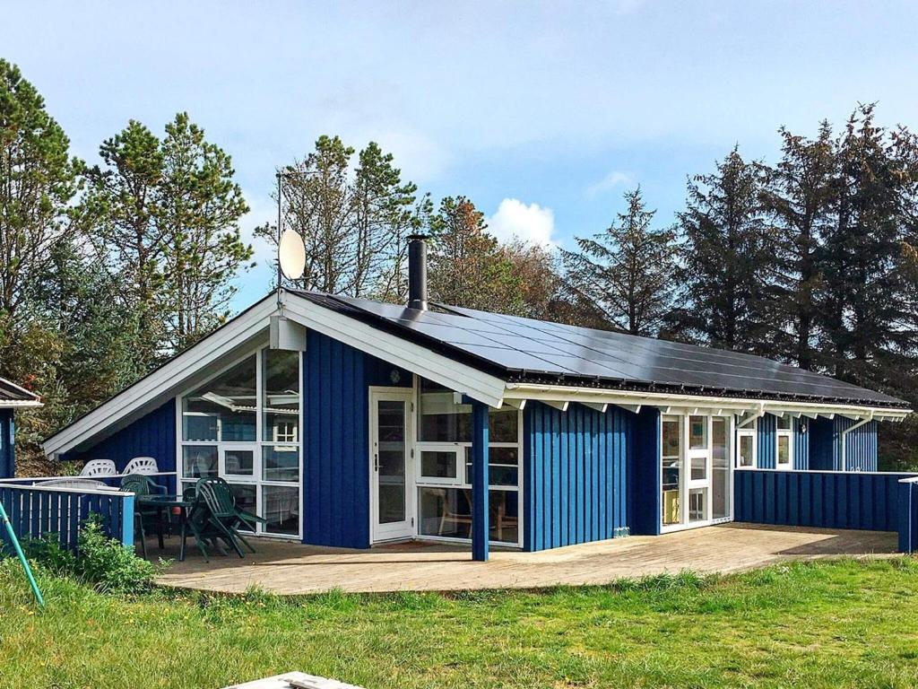 ein blaues Haus mit einer Veranda und einer Terrasse in der Unterkunft 10 person holiday home in lb k in Skram