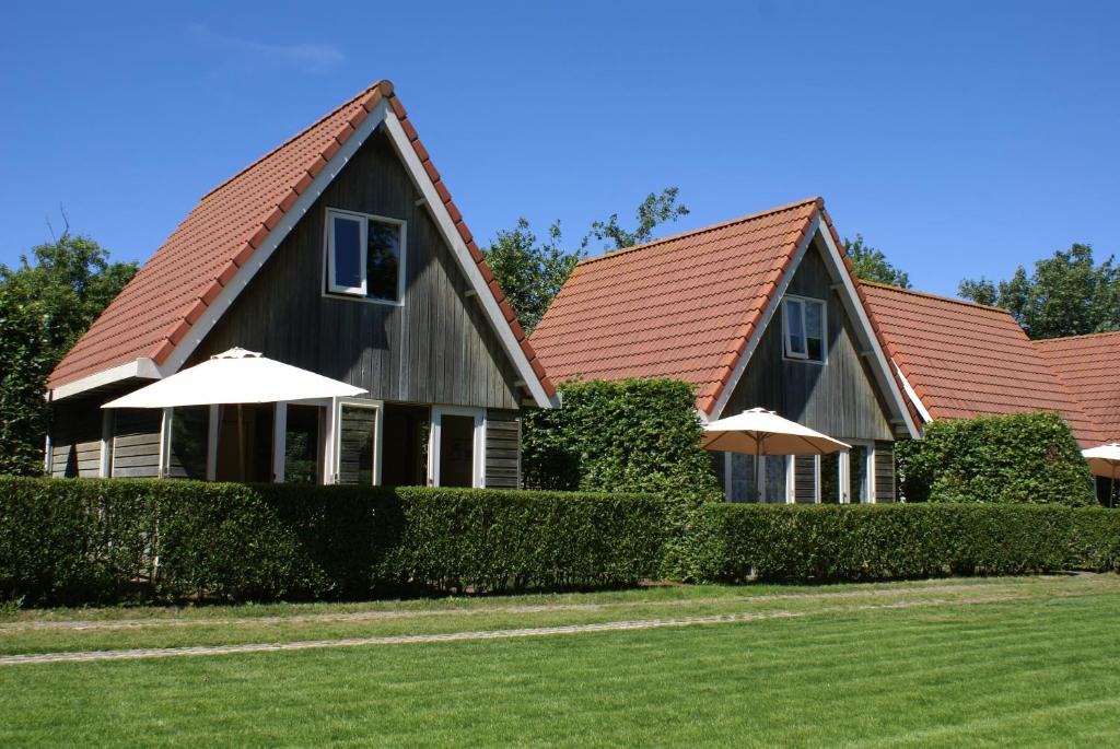 two houses with umbrellas in a yard at Eureka Vakantiehuisjes in Schoorl