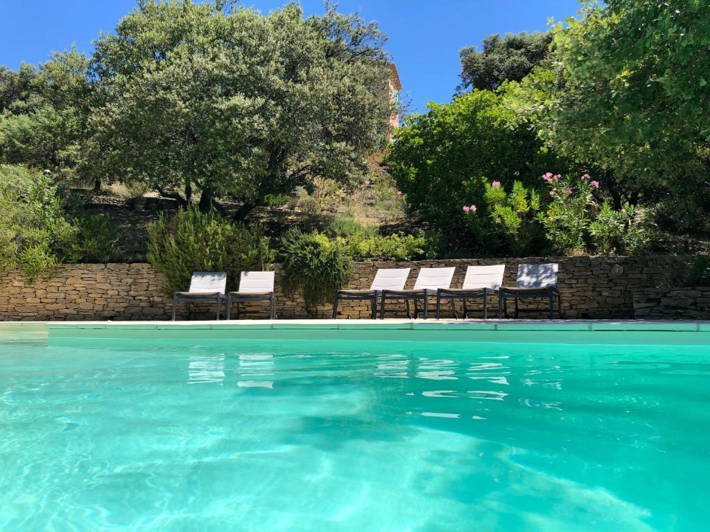 a swimming pool with chairs and blue water at Le Mas du Rocher in Mérindol-les-Oliviers
