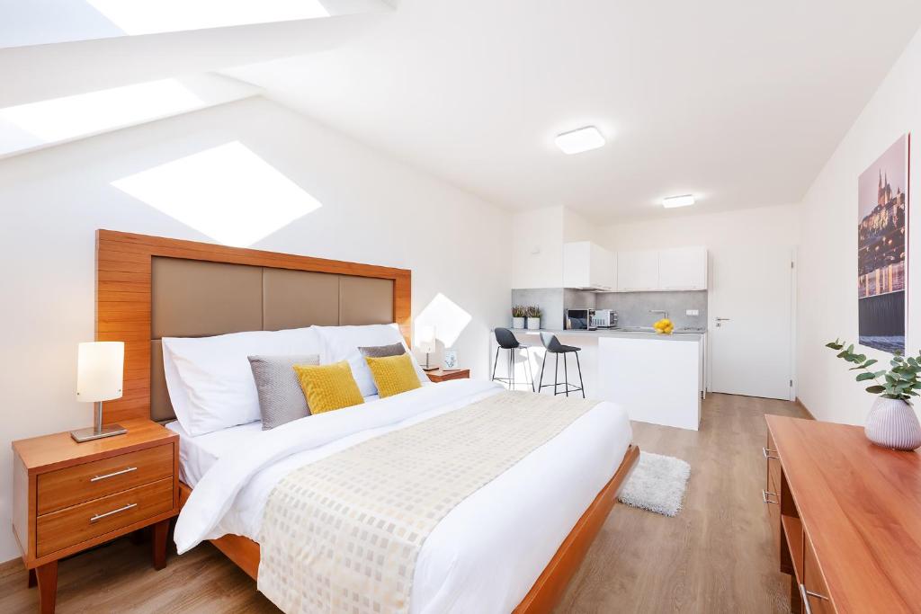 a bedroom with a large bed and a kitchen at Prague Roof Apartments in Prague