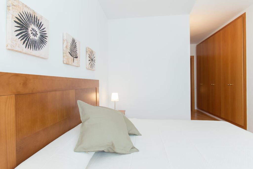 a bedroom with a white bed with a wooden headboard at Sweet Apartments in Sant Pere de Ribes