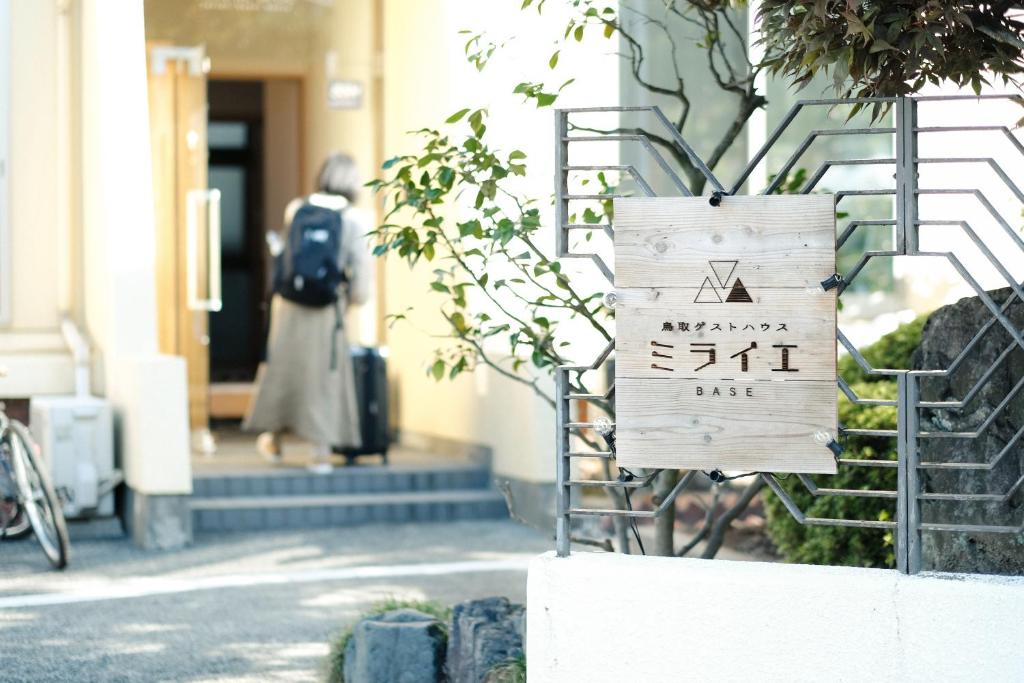 una señal frente a un edificio en Tottori Guest House Miraie BASE, en Tottori