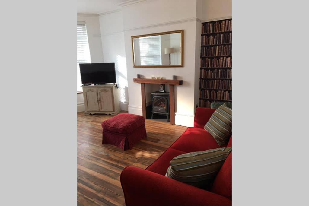 a living room with a red couch and a fireplace at Beach Flat in Birchington