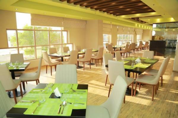 a dining room with tables and white chairs and tablesearcher at Royal View Hotel in Ras al Khaimah