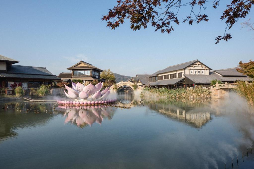 - une vue sur un étang avec un bâtiment en arrière-plan dans l'établissement 拈花湾景区内花园庭院别墅套房---购票入住, à Wuxi